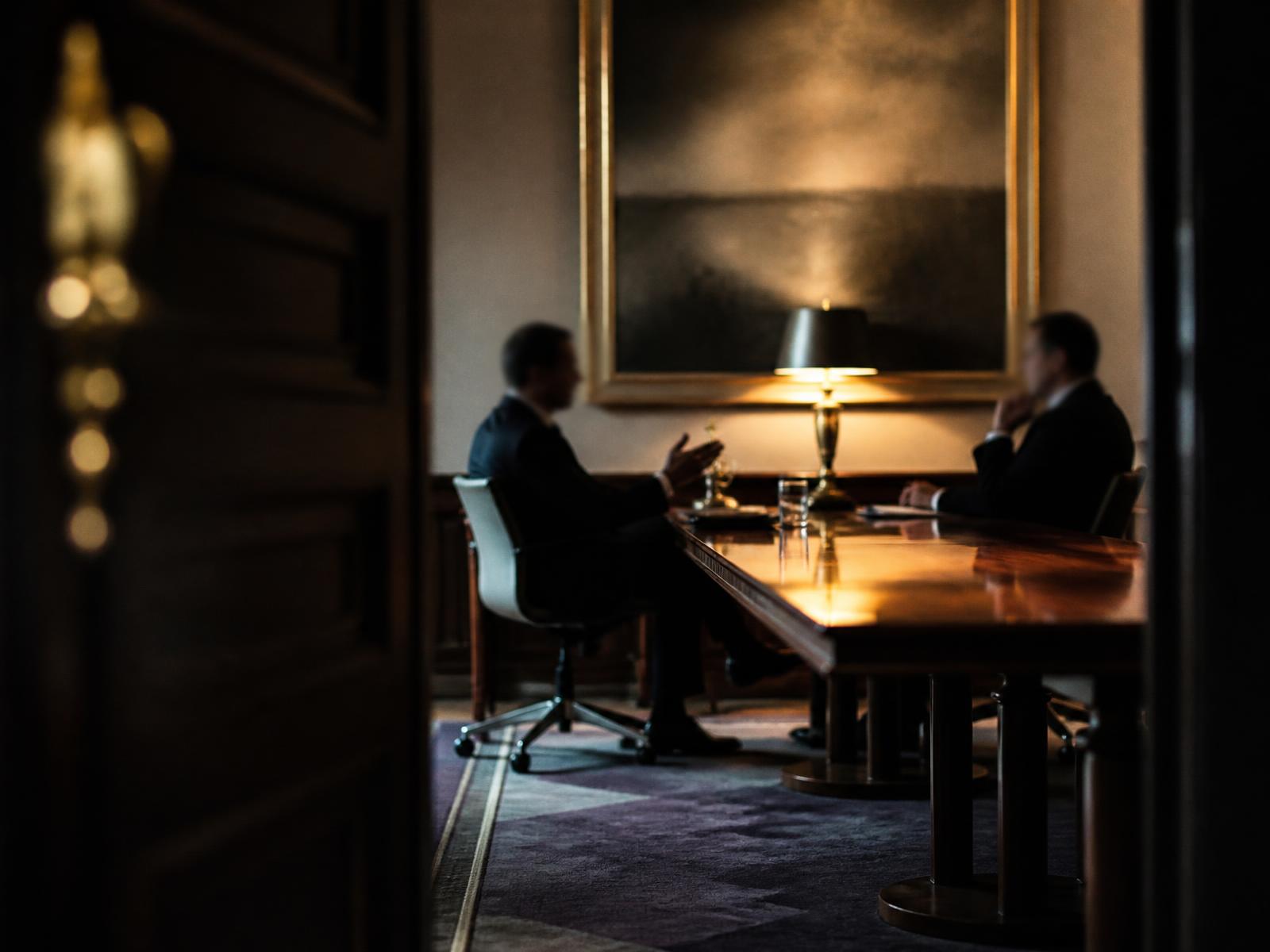 Two advisors in conversation across a boardroom table